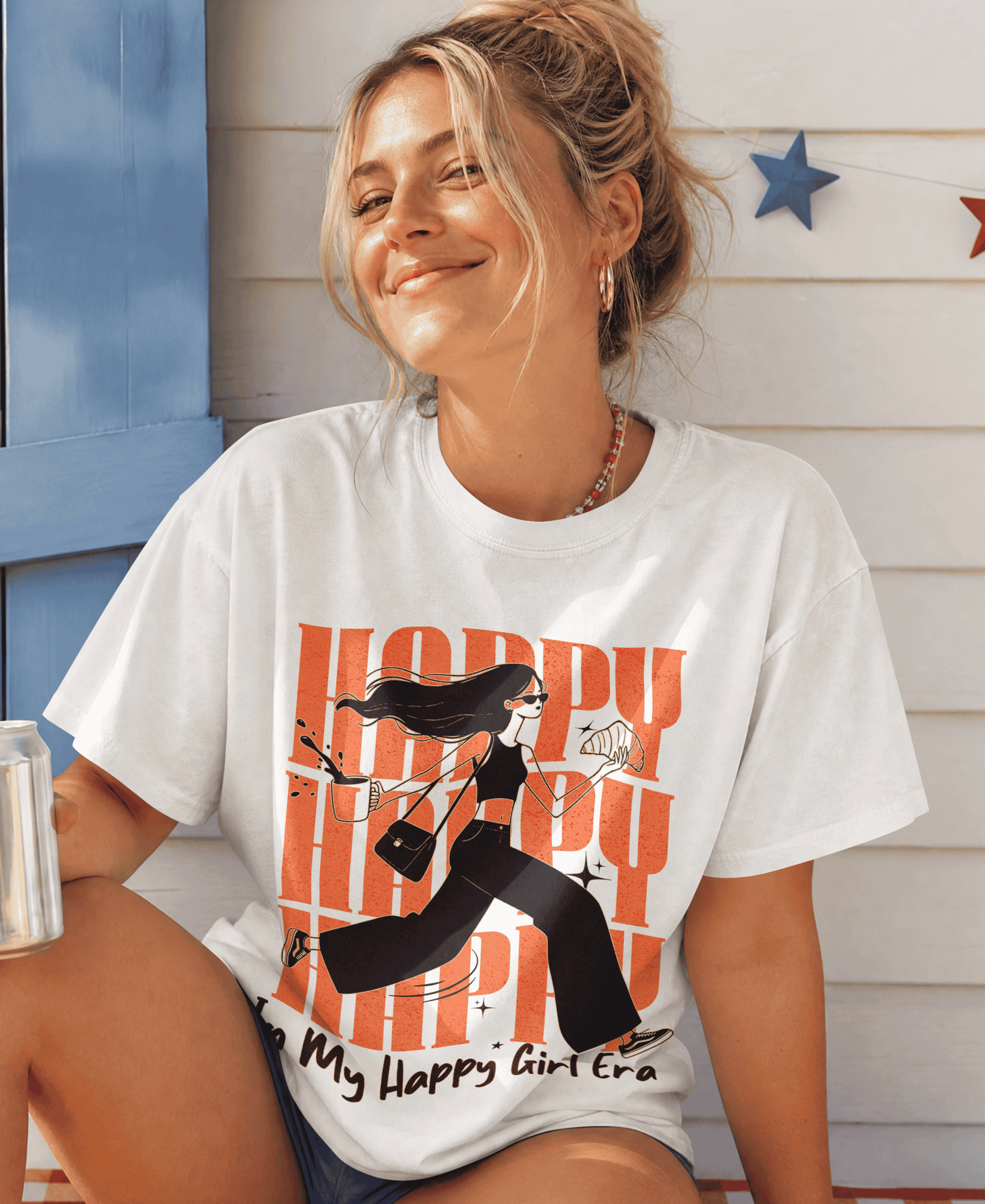 Woman wearing a white t-shirt with graphic design and text, sitting outdoors.